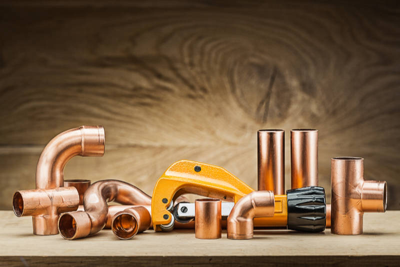 copper pipe fittings and cutter on vintage wood background