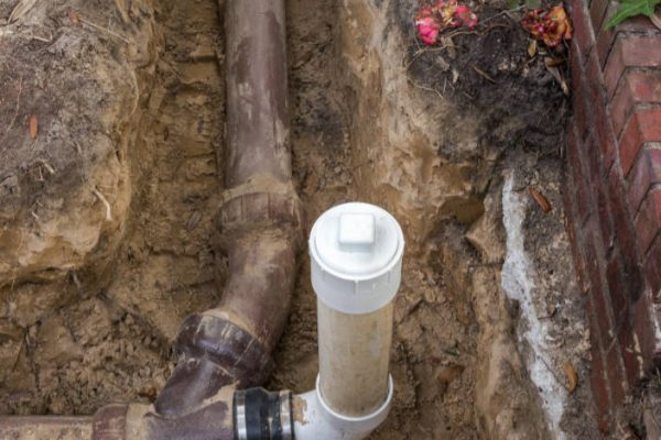 New PVC clean out installed in trench, attached to old ceramic clay pipes on sewer line